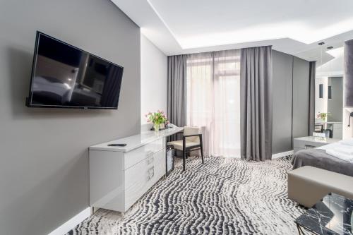 a hotel room with a bed and a desk with a television at SeaPark Hotel Wellness & Spa in Kołobrzeg
