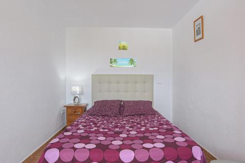 sypialnia z łóżkiem z fioletową kołdrą w obiekcie Apartamento Villa Mayo C w mieście Conil de la Frontera