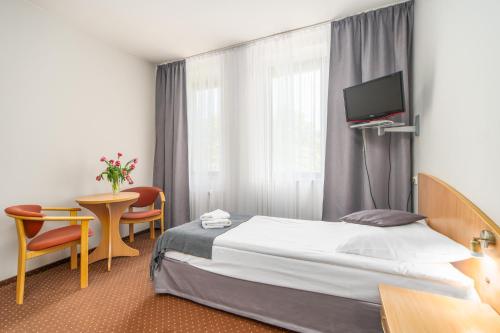 a hotel room with a bed and a table and a tv at SeaPark Hotel Wellness & Spa in Kołobrzeg