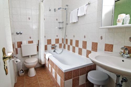 a bathroom with a tub and a toilet and a sink at Wald-Hotel in Troisdorf