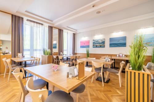 a restaurant with wooden tables and chairs at SeaPark Hotel Wellness & Spa in Kołobrzeg