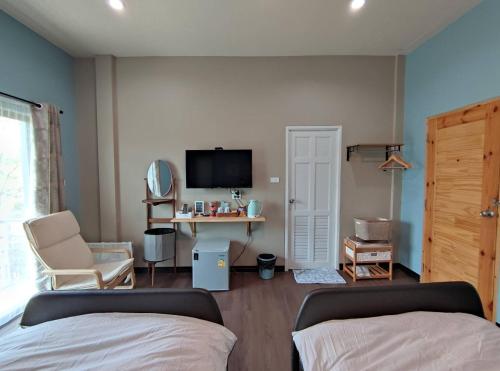 a bedroom with a bed and a tv and a chair at Morinaka Craftfe & Poshtel in Ban Na Muang