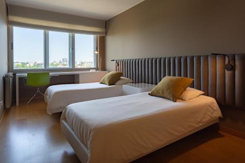ヴィラ・ノヴァ・デ・ガイアにあるCasa da Cidadeのベッド2台と窓が備わるホテルルームです。