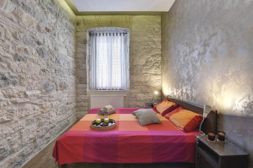 Mimoza Old Town Pula Apartments في بولا: غرفة نوم مع سرير وردي مع وعاء من الفواكه عليه