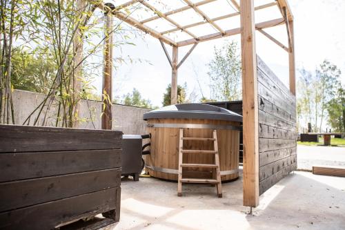 a wooden sauna with a wooden ladder next to a building at Glamplodge met privé sanitair in Blesdijke