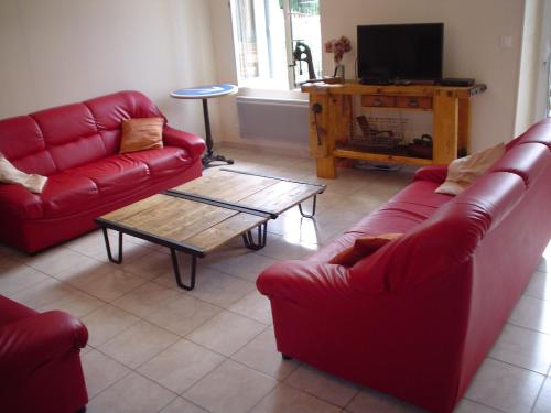 a living room with two red couches and a coffee table at Les Gites de la Musardière in Meusnes