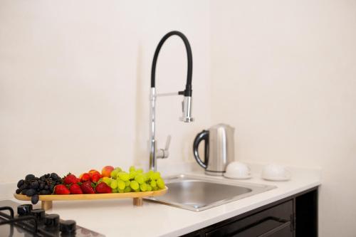a kitchen sink with a tray of fruit on a counter at MYMOON Neas in Noto