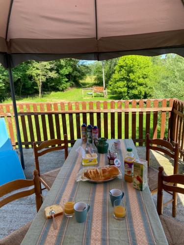 a picnic table under an umbrella with food on it at Gîte du Moulin in Gamarde-les-Bains