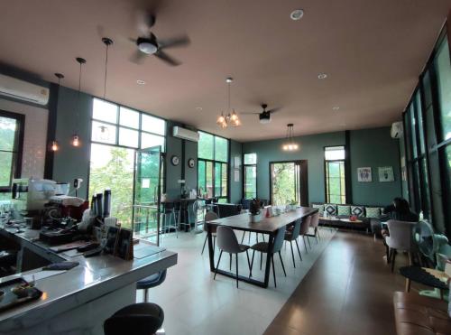 a dining room with a table and chairs and windows at Morinaka Craftfe & Poshtel in Ban Na Muang