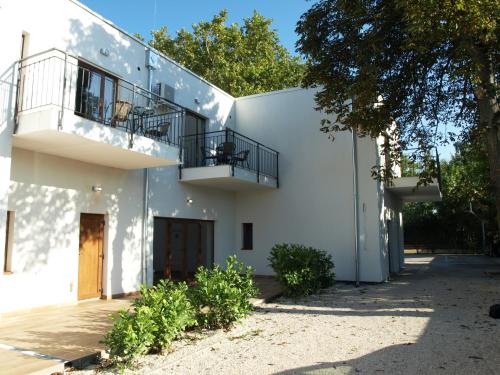 a white building with a porch and a balcony at Garden Club Panzió in Balatonmáriafürdő
