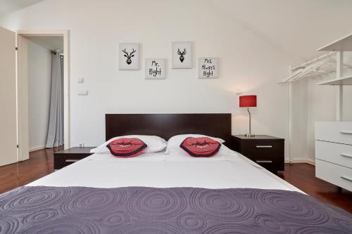 a bedroom with a large white bed with two red pillows at Apartments Gea Trogir in Trogir