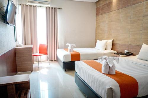 een hotelkamer met 2 bedden en een televisie bij Andelir Hotel Simpang Lima Semarang in Semarang