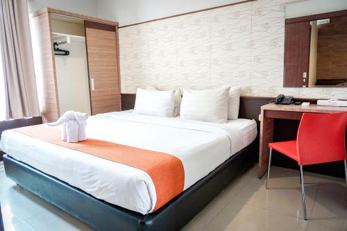 a bedroom with a bed and a desk and a red chair at Andelir Hotel Simpang Lima Semarang in Semarang