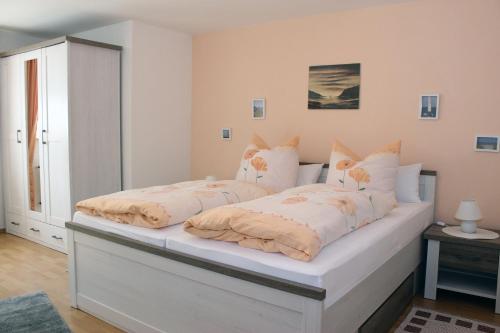 um quarto com uma cama branca com almofadas em Ferienwohnung Bahnsen em Lügde