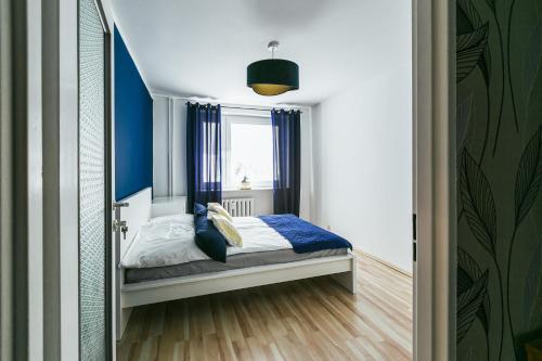 sypialnia z łóżkiem z niebieskimi zasłonami i oknem w obiekcie Apartament w Centrum III w Ustce
