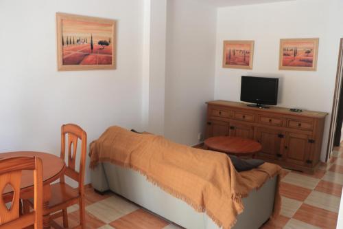 1 dormitorio con cama, mesa y TV en Apartamento San José Obrero, en Conil de la Frontera