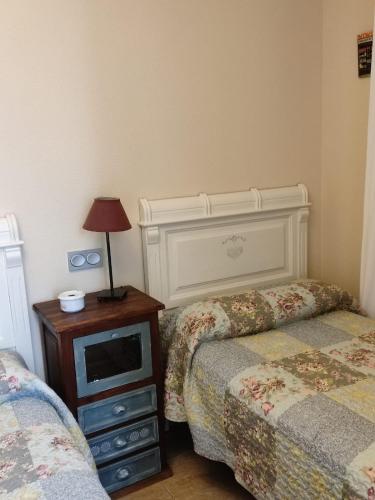 a bedroom with two beds and a table with a lamp at Apartamentos Costa Noja in Noja