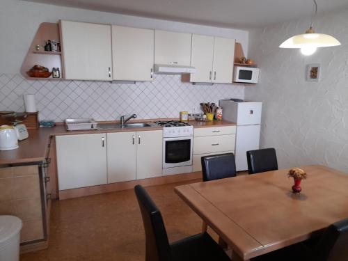 a kitchen with white cabinets and a wooden table with a tableablish at Hiša Pepi in Ajdovščina