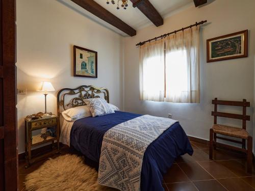 a bedroom with a bed with a blue blanket and a window at Finca Engracia in Cudillero