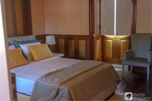 a bedroom with a large bed and a chair at Quinta da Urtigueira in Felgueiras