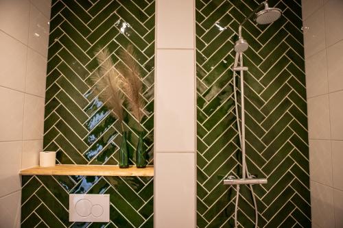 baño con ducha de azulejos verdes en Natuur lodge en Blesdijke