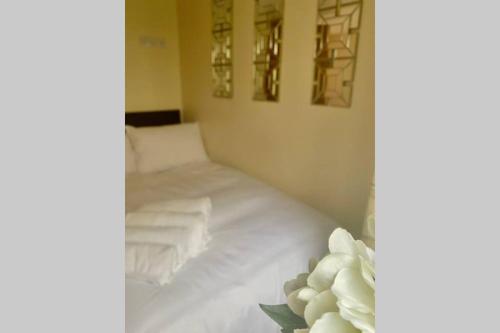 a bed with white sheets and towels on it at Beautiful Bijou Bungalow in Gloucester