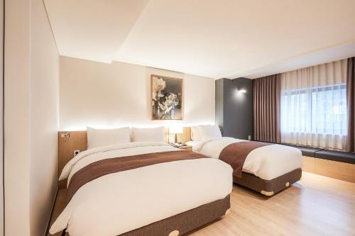 a hotel room with two beds and a window at Eden Paradise Hotel in Icheon