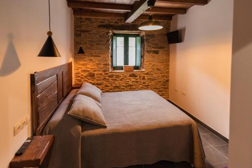 a bedroom with a bed and a brick wall at Apartamentos Rurales Casa Llongo in Coaña