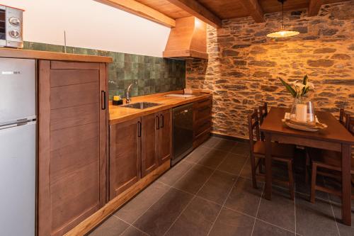 a kitchen with wooden cabinets and a table and a refrigerator at Apartamentos Rurales Casa Llongo in Coaña