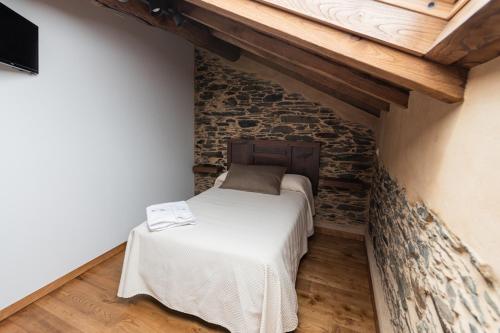 um pequeno quarto com uma cama numa parede de tijolos em Apartamentos Rurales Casa Llongo em Coaña