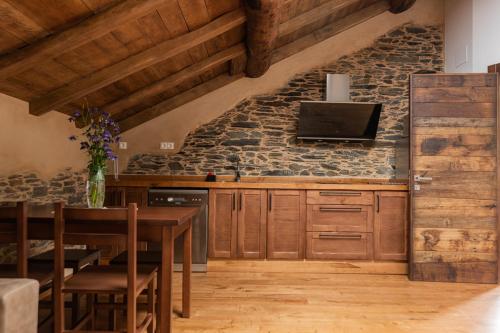 a kitchen with wooden cabinets and a stone wall at Apartamentos Rurales Casa Llongo in Coaña