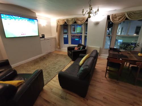 a living room with leather furniture and a large screen at Huge 6-Bed Apartment in Darlington Centre in Darlington