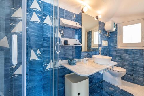 W wyłożonej niebieskimi kafelkami łazience znajduje się umywalka i toaleta. w obiekcie Seafront Villa with private pool w mieście Marongiu