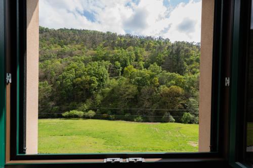 a window with a view of a field and trees at Apartamentos Rurales Casa Llongo in Coaña