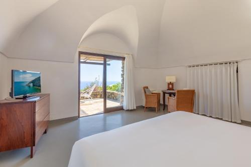 Pantelleria Dream Resort في بانتيليريا: غرفة نوم بسرير ومكتب مع تلفزيون