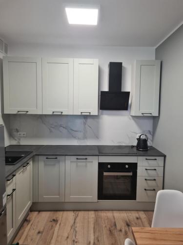 a kitchen with white cabinets and a black appliance at Apartament w Centrum IV in Ustka