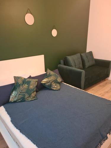 a bed with pillows and a couch in a room at Apartament w Centrum IV in Ustka