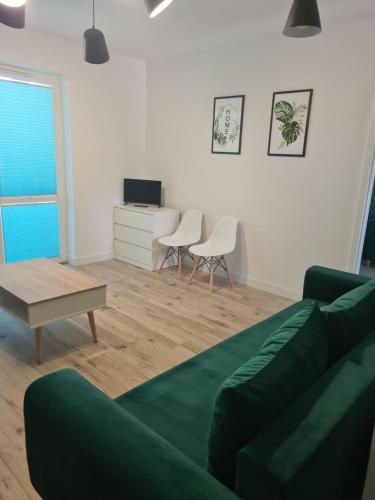 a living room with a green couch and a table at Apartament w Centrum IV in Ustka