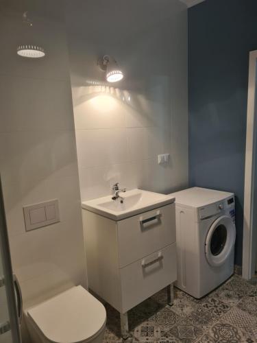 a bathroom with a toilet and a sink and a washing machine at Apartament w Centrum IV in Ustka