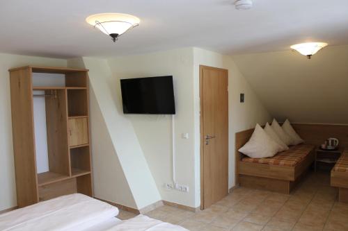 a room with a bed and a tv on the wall at Landhotel Guglhupf in Schwangau