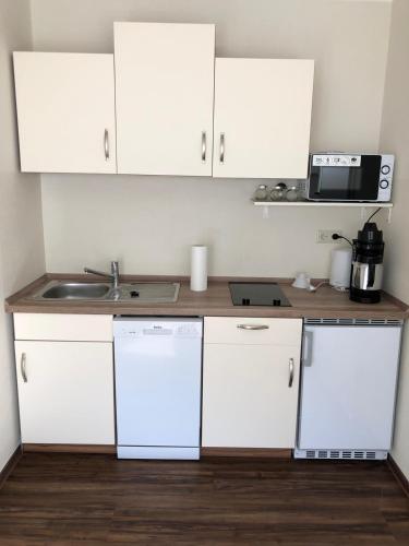 a kitchen with white cabinets and a sink at Auszeit am Eifelsteig in Daun