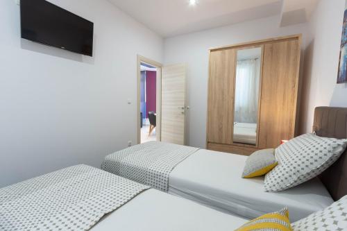 a bedroom with two beds and a television on the wall at Apartman Dora in Podstrana