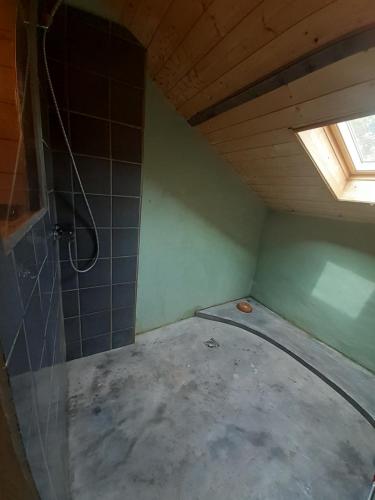 an attic room with a shower and a window at La maison parfumée in La Valade