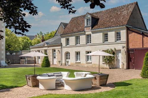 two white chairs and umbrellas in front of a house at Le Clos Richelieu in Amboise