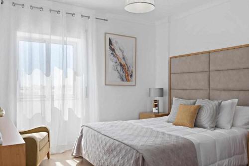 a white bedroom with a large bed and a window at Timeless Sea I Apartment in Armação de Pêra
