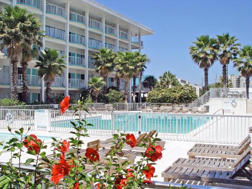 a hotel with a swimming pool and palm trees and flowers at Boardwalk Beach Hotel in Panama City Beach