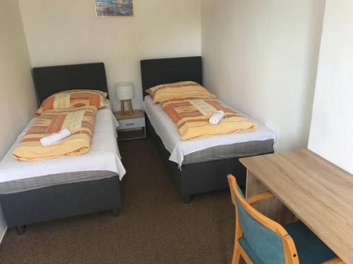 two twin beds in a room with a table and a table sidx sidx at Pension Berten Strašice in Strašice