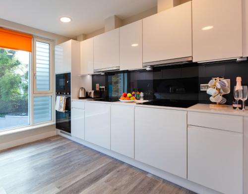 a kitchen with white cabinets and a large window at The Westwood Apartments in Galway