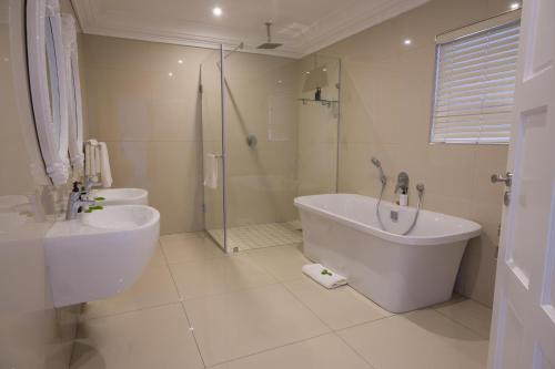 a bathroom with two sinks and a tub and a shower at The View Boutique Hotel & Spa in Amanzimtoti