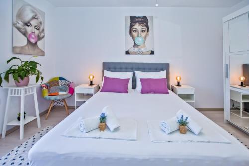 1 dormitorio con 1 cama blanca grande con almohadas moradas en Apartments and Rooms Marija, en Hvar